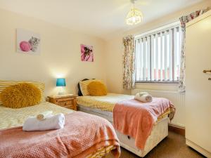 1 dormitorio con 2 camas y ventana en Pear Tree Cottage en Banham