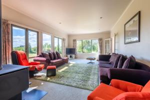 a living room with couches and a tv and windows at Big Inn Brunswick in Rotorua