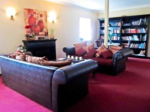 sala de estar con 2 sofás de cuero y chimenea en Hotel Flora, en Fredersdorf
