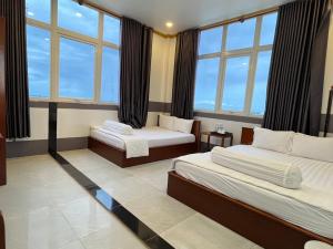 um quarto de hotel com duas camas e grandes janelas em Khách sạn Vân Nhi em Bạc Liêu