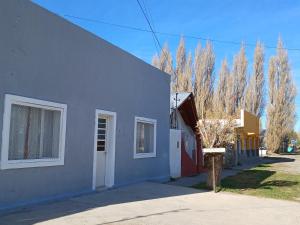una casa azul y blanca con árboles en el fondo en Alojamiento Río Fenix Chico en Perito Moreno