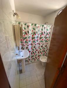 Un baño con inodoro y cortina de ducha. en Cabañas K&M, en La Falda
