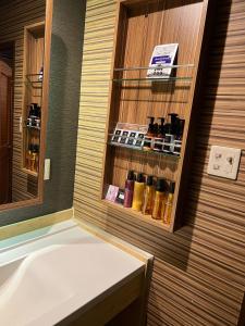 uma casa de banho com banheira e uma prateleira com garrafas em ホテルアシュエル em Minatomachi