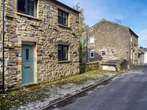 an old stone building with a green door on a street at May Cottage - Uk12970 in Settle