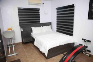 um pequeno quarto com uma cama e uma passadeira em Dabb Apartments em Ilorin