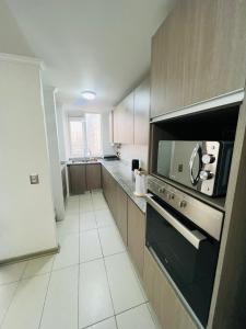 a kitchen with a stove and a microwave at Apartamento vista al mar in Iquique
