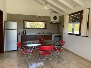uma cozinha com uma mesa de vidro e cadeiras vermelhas em Viento y montaña em San Carlos de Bariloche