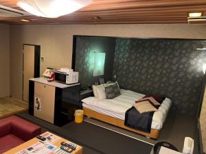 a small bedroom with a bed and a microwave at ホテルアシュエル in Minatomachi