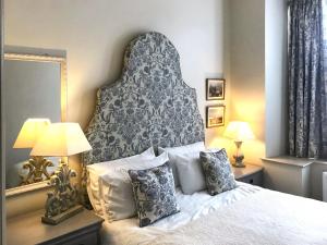 a bedroom with a bed with a large headboard and two lamps at Harrow House in Berwick-Upon-Tweed