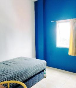 um quarto azul com uma cama e uma janela em Kost Griya Hikari by Ecommerceloka em Jakarta