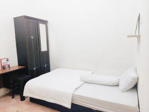 um quarto com uma cama branca e um armário preto em Kost Griya Hikari by Ecommerceloka em Jakarta