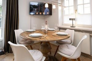 een eetkamer met een houten tafel en witte stoelen bij Ferienhaus-Hoppe-Wohnung-01 in Westerland