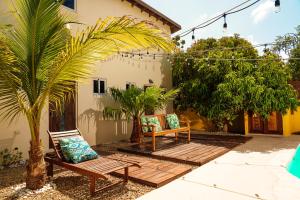Savaneta的住宿－Anaté Beach Apartments, Mangel Alto，两把椅子和一棵棕榈树,在房子前面