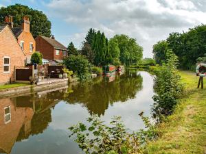 a river in a town with houses and a person holding an umbrella at Wilne Cottage in Shardlow