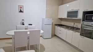 een keuken met witte apparatuur en een witte tafel en stoelen bij Casa de férias com 2 quartos ou aluguer diária in Praia