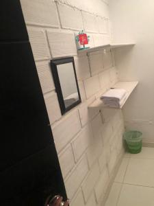 a bathroom with white tiled walls and a mirror at Hostal Mía Apá in Necoclí