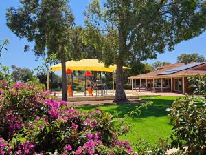 un pabellón con parque infantil en un parque con flores en Banksia Tourist Park en Perth
