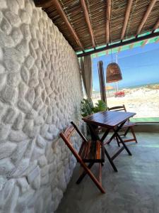 uma mesa e cadeiras sentadas ao lado de uma parede de pedra em Flats Villas Litoral Sul - Praia Pontal do Peba - Piaçabuçu - AL em Piaçabuçu