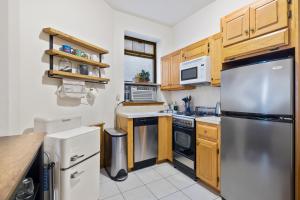 uma cozinha com armários de madeira e um frigorífico de aço inoxidável em Central Living at Columbia university em Nova York