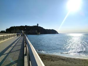 a pier with people walking on the beach with a rainbow at 江の島の頂上から海を眺める一棟ヴィラ 一組限定貸切 The ENOSHIMA Villa AO in Fujisawa