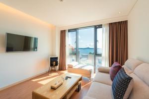 a living room with a couch and a large window at Hotel Fine Jeju in Seogwipo