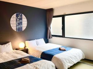 - 2 lits dans une chambre avec fenêtre dans l'établissement 民泊Murakami International, à Kishiwada