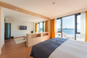 Hotel Fine Jeju في سيوجويبو: غرفة نوم بسرير كبير ونافذة كبيرة