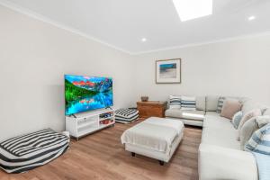 uma sala de estar com um sofá branco e uma televisão de ecrã plano em 11 Esprit Drive - Rainbow Shores. Swimming Pool - Wifi - Walk to beach em Rainbow Beach