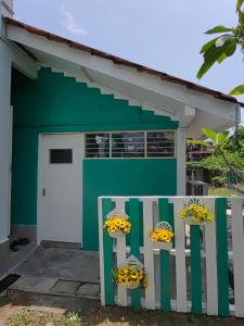 a green and white building with two windows and flowers at FA House by the Beach in Tanjung Bungah