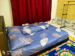 a bed with a blue comforter and a red curtain at HrL Homestay Kangar in Kangar