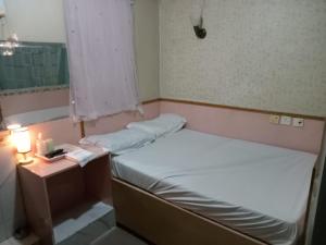 a small room with two beds and a table with a lamp at 嘉湖旅館 in Hong Kong