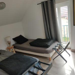 a bedroom with a bed and a chair and a window at Le Val d'Andé chez habitant 6 lits individuels in Andé