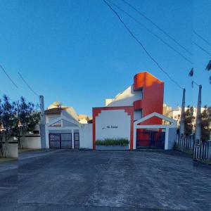 ein weißes und rotes Gebäude vor einer Straße in der Unterkunft Triplex White em Caiobá-Matinhos-Pr a 200 mt do mar in Matinhos