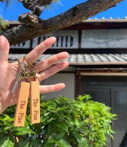 una persona che tiene due targhette su un albero di The Pine 京都嵐山 a Kyoto