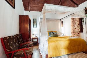 ein Schlafzimmer mit einem Himmelbett und einem Stuhl in der Unterkunft Safariland Home stay in Arusha