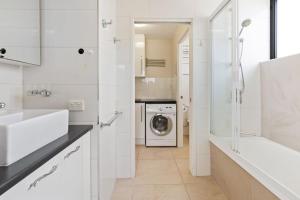 a white bathroom with a washing machine and a washer and dryer at Eastbourne U6 80 Esplanade Golden Beach in Caloundra