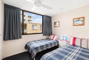 two beds in a room with a window at Eastbourne U6 80 Esplanade Golden Beach in Caloundra