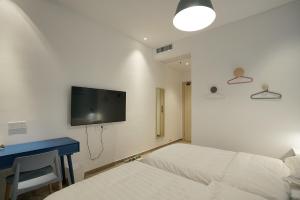1 dormitorio con 2 camas, escritorio y TV en Swan's Journey International Youth Hostel - Changsha Wuyi Square IFS IFC, en Changsha