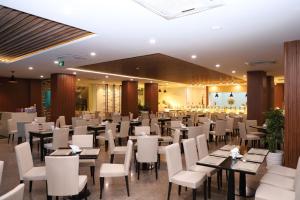 a dining room with tables and white chairs at TTC Hotel - Can Tho in Can Tho