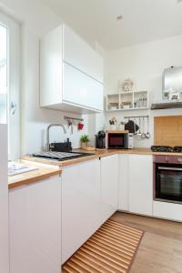 uma cozinha branca com armários brancos e um lavatório em Casa Serena - Meryggiare Apartments em Milão