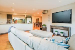 sala de estar con muebles blancos y TV de pantalla plana en Loka 7 beachfront apartment, en Agnes Water