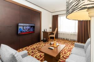 a living room with two chairs and a table and a tv at Swiss-Belinn Baloi Batam in Nagoya