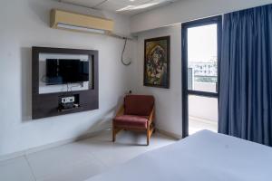 a bedroom with a bed and a chair and a window at Hotel Parkland Manage by G Express in Ahmedabad