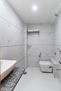 a white bathroom with a tub and a toilet at Hotel Parkland Manage by G Express in Ahmedabad
