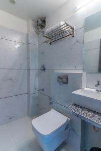 a white bathroom with a toilet and a sink at Hotel Parkland Manage by G Express in Ahmedabad