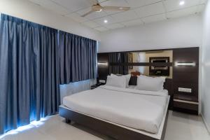 a bedroom with a large bed with blue curtains at Hotel Parkland Manage by G Express in Ahmedabad