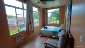 um quarto com uma cama, uma cadeira e janelas em Boca Chica BnB at Gone Fishing Panama Resort em Boca Chica