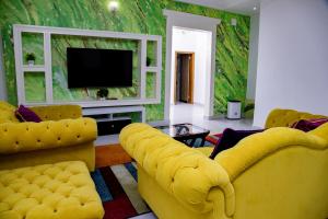 a living room with yellow furniture and a tv at PINORICH VILLA-Buea in Buea