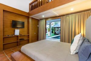 Un dormitorio con una cama grande y un televisor. en Buddha Beach Villa Seminyak, en Seminyak 12 fotos más