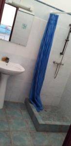 La salle de bains est pourvue d'une douche avec un rideau de douche bleu. dans l'établissement LE ZAGOUTI, à Capesterre